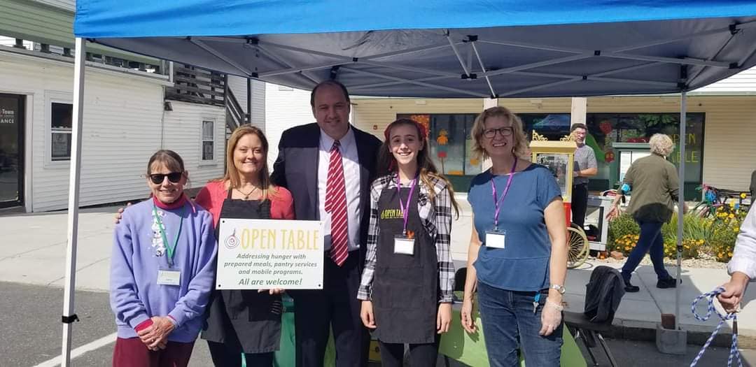 Five people under a blue tent outside of Open Table