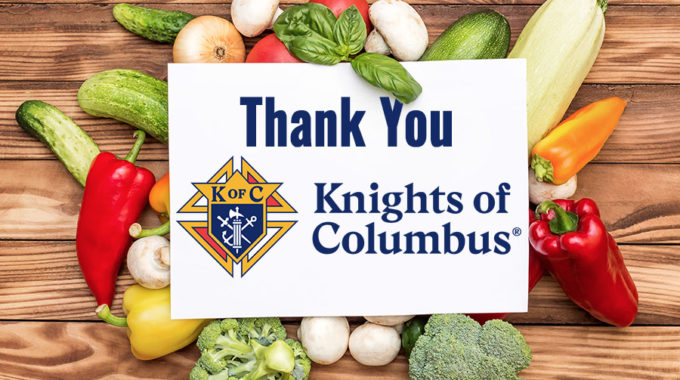 Cutting board with produce and white sign in the middle that says Thank You Knights of Columbus