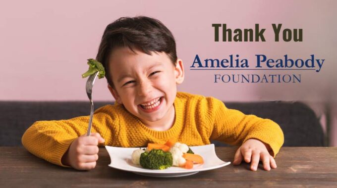 Boy with dark hair and yellow sweater holding up a piece of broccoli with a plate of cooked vegetables in front of him - he is smiling. The words Thank You to his right and the Amelia Peabody Logo below