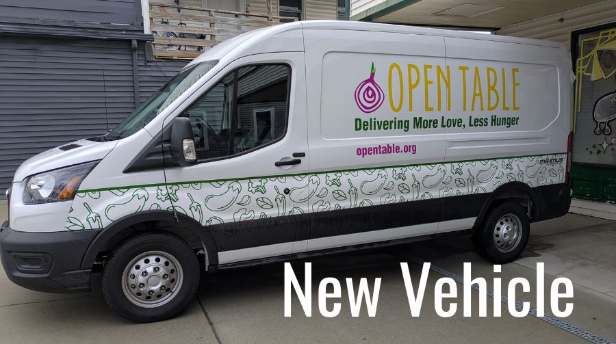 White sprinter van with Open Table logo on the side. The words "New Vehicle" in white at the bottom.