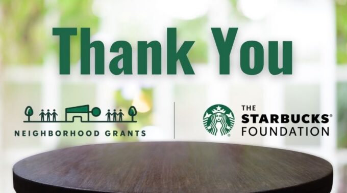 A dark brown round table in the foreground with a blurred background and the words "Thank You" in dark green at the top. The Neighborhood grants Starbucks Foundation logo in between.